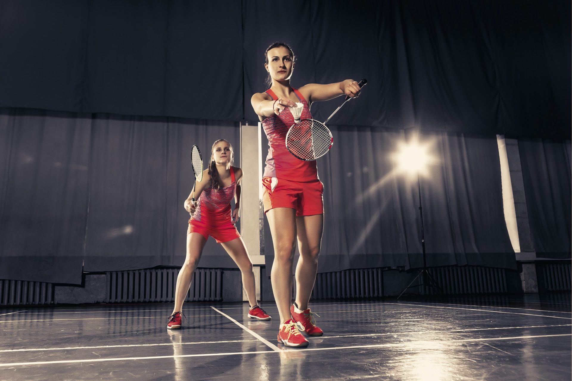 Young women playing badminton at gym 1 e1657173703217.jpg