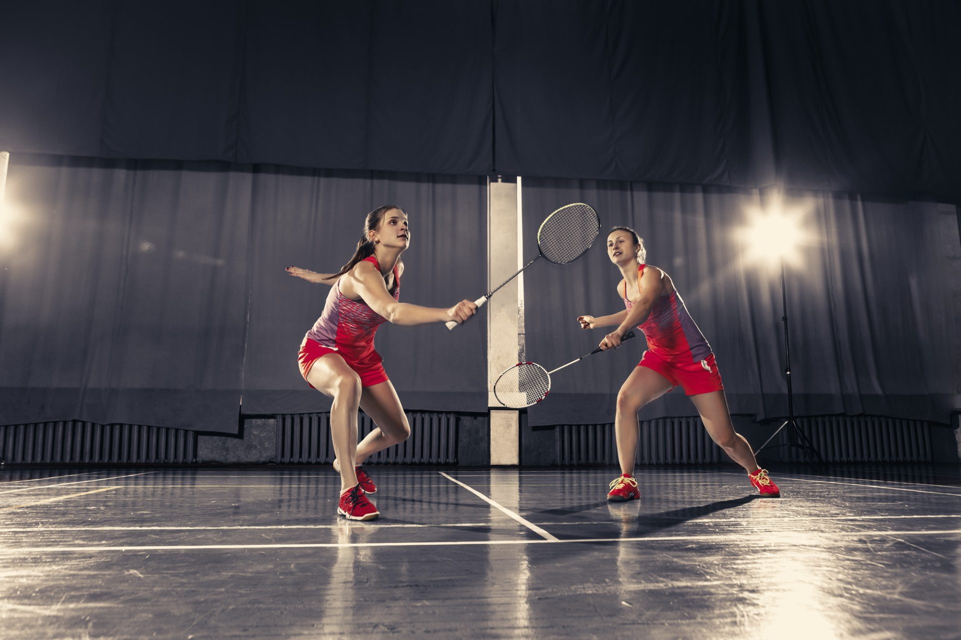 Young women playing badminton at gym e1657172609286.jpg